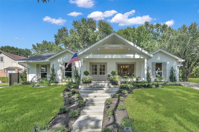 view of front of property featuring a porch, a front yard, and french doors