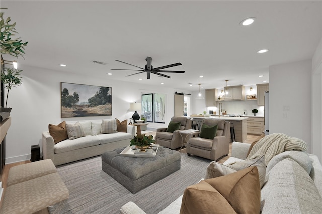 living area featuring recessed lighting, visible vents, light wood finished floors, and a barn door