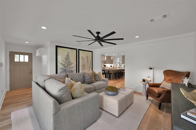 living area featuring baseboards, light wood-type flooring, visible vents, and recessed lighting