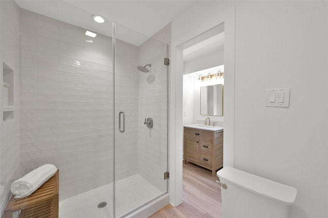 bathroom featuring a stall shower, vanity, toilet, and wood finished floors