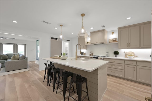 kitchen with stainless steel stove, light countertops, visible vents, a barn door, and light wood-style floors