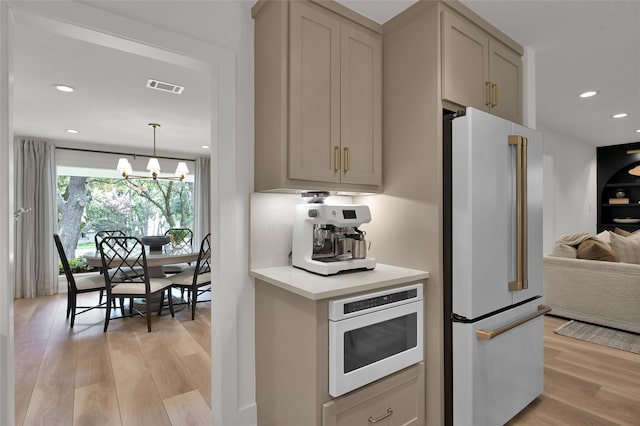 kitchen with light wood finished floors, high end fridge, light countertops, visible vents, and white microwave