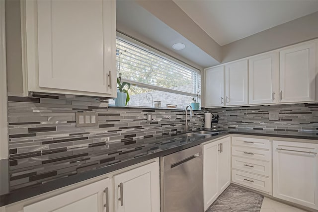 kitchen with dark countertops, tasteful backsplash, white cabinets, and dishwasher