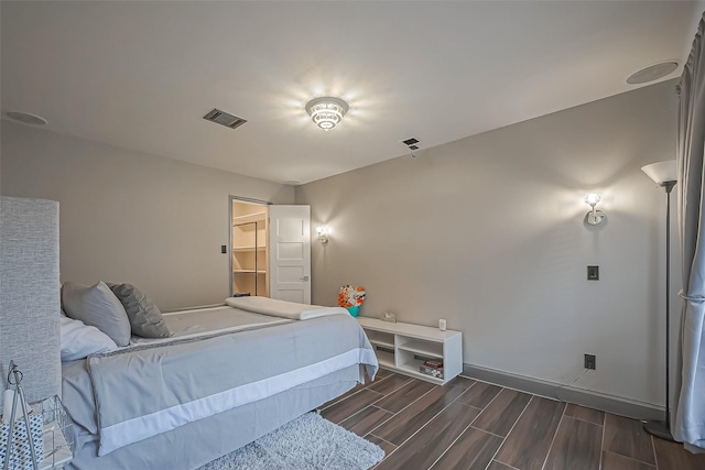 bedroom featuring wood finish floors, visible vents, and baseboards