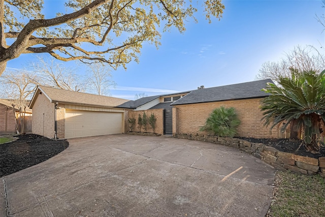 mid-century home with brick siding, a detached garage, and roof with shingles