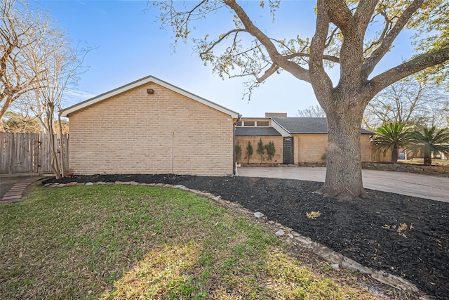 view of home's exterior with a yard, fence, and brick siding