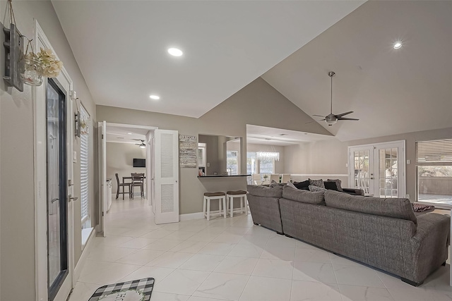 living area with baseboards, light tile patterned flooring, ceiling fan with notable chandelier, high vaulted ceiling, and recessed lighting