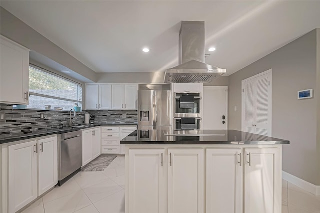 kitchen with island exhaust hood, dark countertops, backsplash, appliances with stainless steel finishes, and a sink