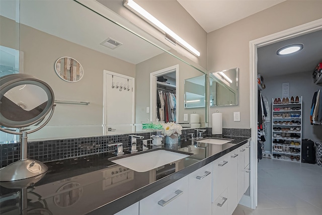 full bath with a walk in closet, visible vents, a sink, and backsplash