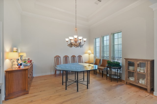 dining area featuring visible vents, ornamental molding, light wood-style floors, a raised ceiling, and a chandelier