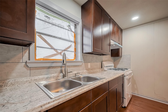 kitchen featuring dark brown cabinetry, a sink, light countertops, white gas stove, and backsplash