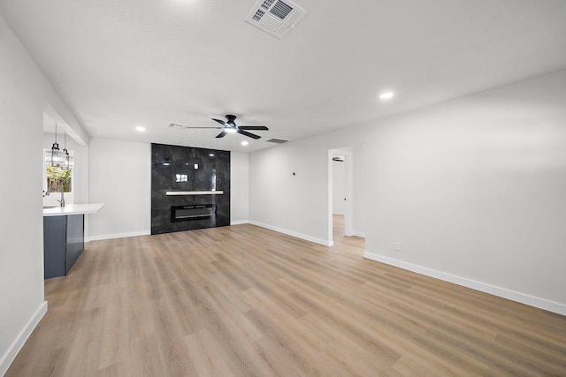 unfurnished living room featuring ceiling fan, recessed lighting, a premium fireplace, visible vents, and light wood finished floors