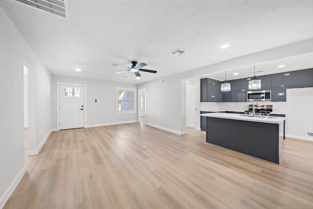 kitchen featuring light countertops, stainless steel microwave, visible vents, light wood-style floors, and modern cabinets