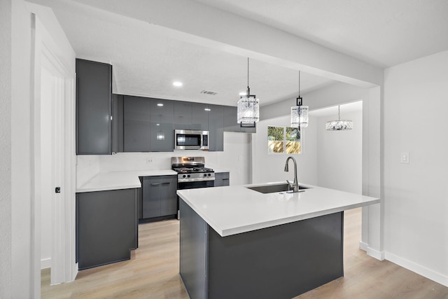 kitchen featuring light wood-style flooring, appliances with stainless steel finishes, light countertops, and a sink