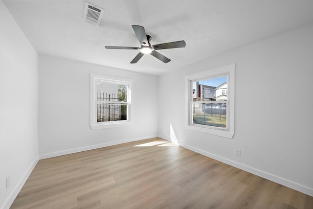 unfurnished room featuring a healthy amount of sunlight, light wood-style floors, baseboards, and visible vents