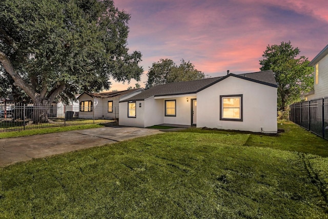 ranch-style house featuring a yard, concrete driveway, fence, and stucco siding