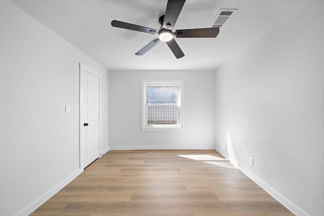 empty room featuring a textured ceiling, light wood-style flooring, visible vents, and baseboards