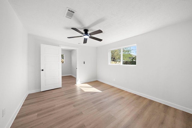 unfurnished bedroom with visible vents, baseboards, light wood-style flooring, ceiling fan, and a textured ceiling