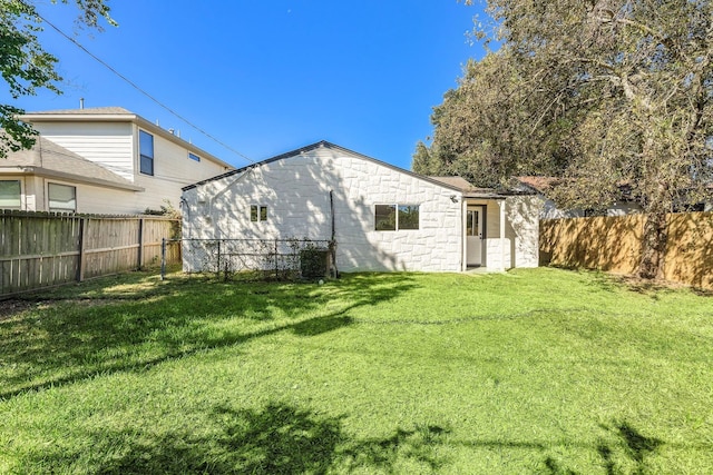 back of property featuring a fenced backyard and a lawn