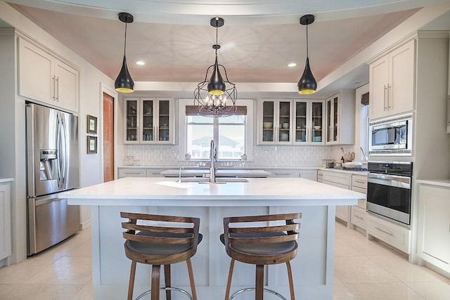 4214 Turks Pt, Galveston, TX 77554 - kitchen featuring an island with sink, appliances with stainless steel finishes, a sink, light countertops, and backsplash