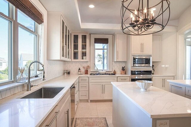4214 Turks Pt, Galveston, TX 77554 - kitchen featuring appliances with stainless steel finishes, backsplash, a sink, and light stone countertops