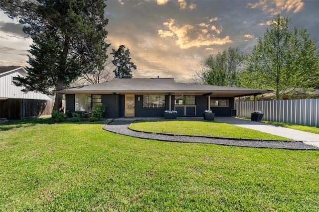 view of front of property featuring fence, a front lawn, an attached carport, and concrete driveway