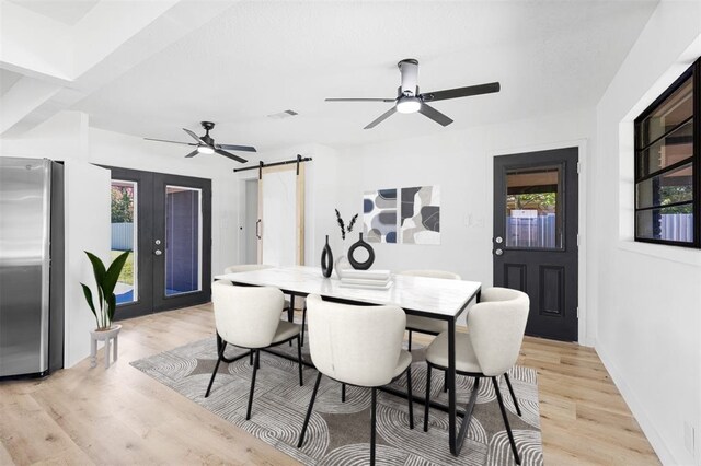 dining room with ceiling fan, a barn door, visible vents, light wood-style floors, and french doors