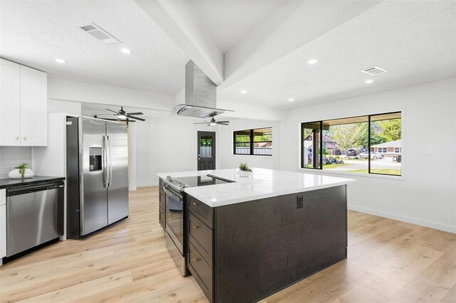 kitchen with visible vents, light wood-style flooring, appliances with stainless steel finishes, white cabinetry, and wall chimney exhaust hood