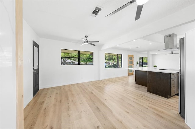 interior space featuring a ceiling fan, visible vents, baseboards, beam ceiling, and light wood finished floors