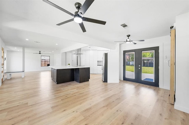 kitchen featuring visible vents, light wood-style flooring, open floor plan, light countertops, and french doors