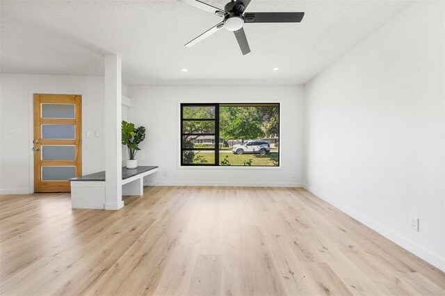 empty room with light wood-style floors, recessed lighting, a textured ceiling, and baseboards