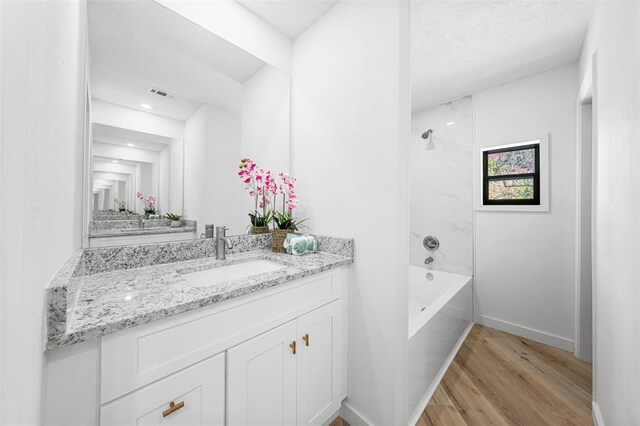 full bath featuring wood finished floors, vanity, visible vents, and baseboards