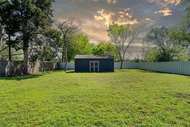 yard at dusk with a storage shed, an outdoor structure, and a fenced backyard