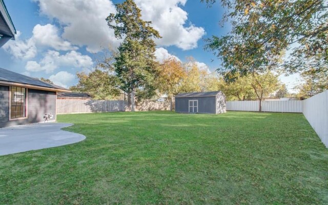 view of yard with an outbuilding, a fenced backyard, a patio, and a storage shed