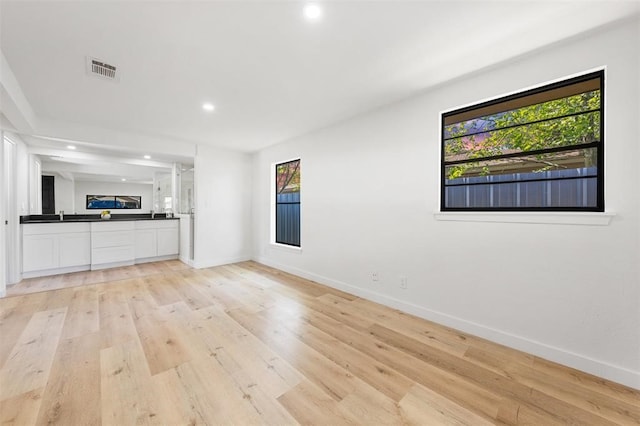 unfurnished living room featuring light wood finished floors, recessed lighting, visible vents, and baseboards