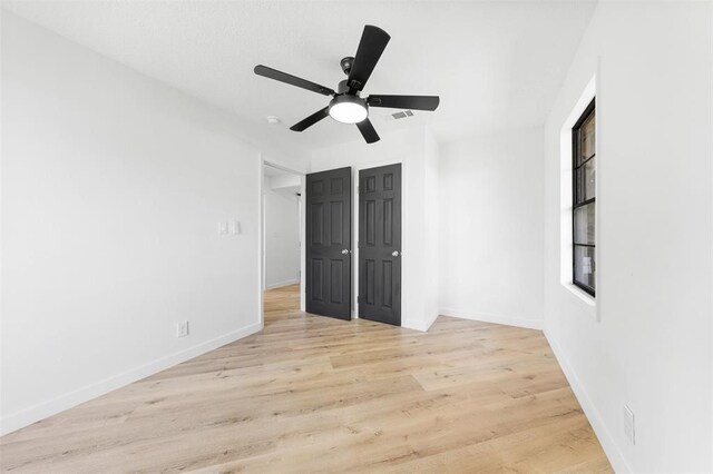 unfurnished bedroom featuring ceiling fan, visible vents, baseboards, and wood finished floors