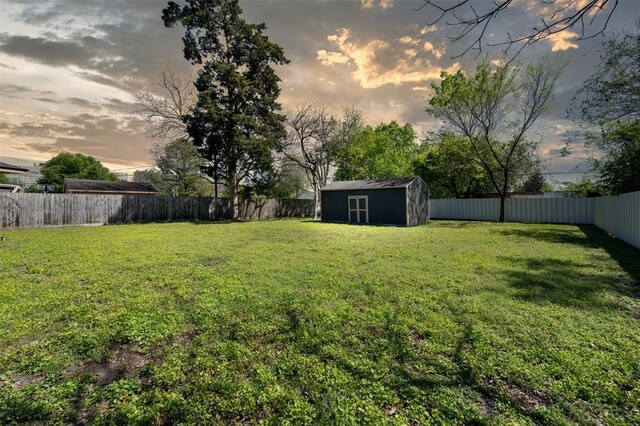 view of yard featuring a fenced backyard, an outdoor structure, and a storage shed