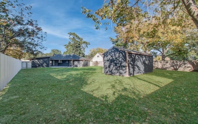 view of yard with a fenced backyard, an outdoor structure, and a shed