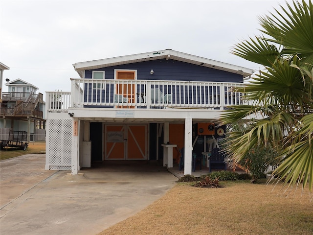 back of house with a carport, driveway, and a wooden deck