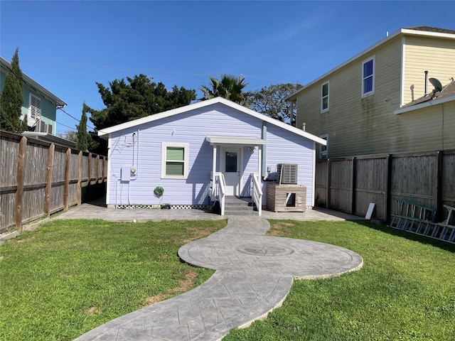 back of property with a fenced backyard and a lawn