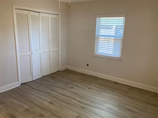 unfurnished bedroom featuring a closet, wood finished floors, and baseboards