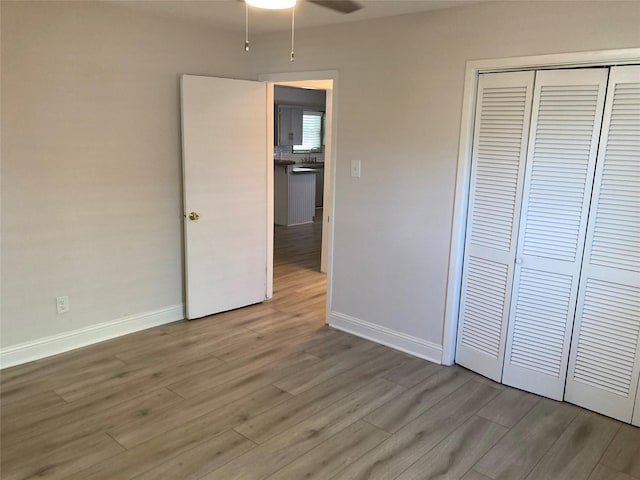 unfurnished bedroom with a closet, baseboards, and wood finished floors