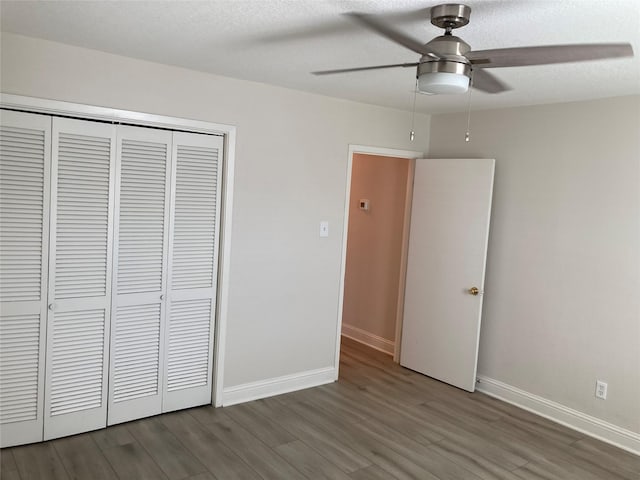 unfurnished bedroom featuring a closet, a textured ceiling, baseboards, and wood finished floors