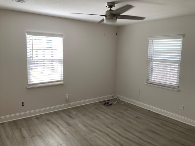 spare room with a ceiling fan, a textured ceiling, baseboards, and wood finished floors