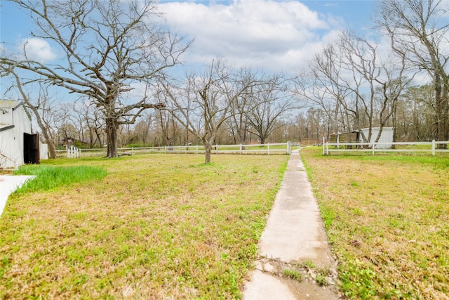 view of yard with an outbuilding, a rural view, and fence