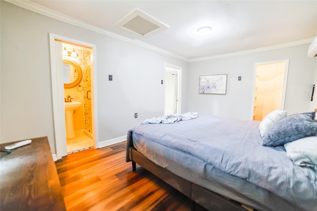 bedroom with attic access, crown molding, baseboards, and wood finished floors