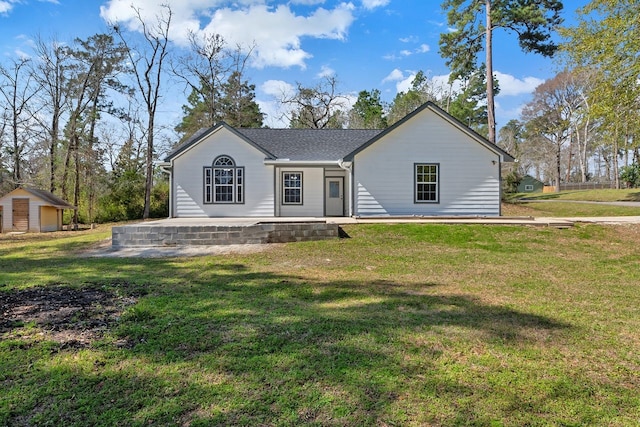 view of front of house with an outbuilding, a front lawn, and roof with shingles