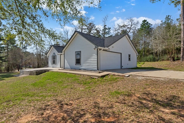 view of side of property with concrete driveway, a lawn, and an attached garage