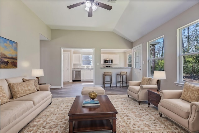 living area with lofted ceiling, a healthy amount of sunlight, and wood finished floors