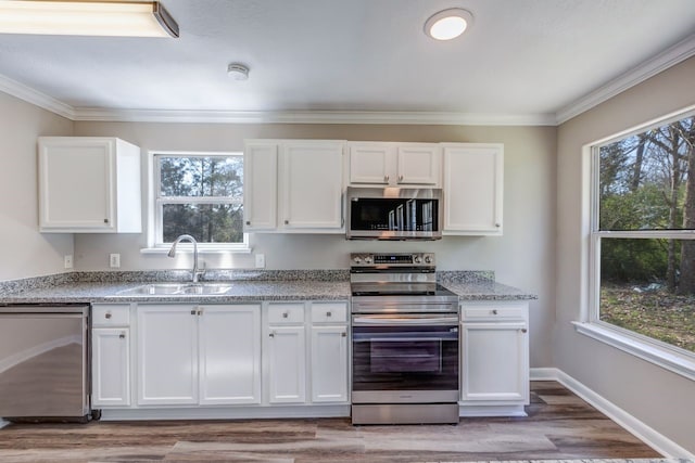 kitchen featuring appliances with stainless steel finishes, white cabinetry, a sink, and crown molding